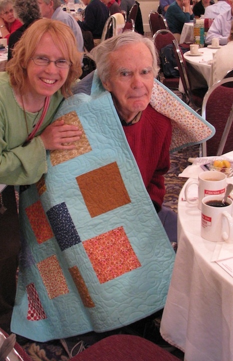 A daughter wraps her father in a quilt by Bob Johnson